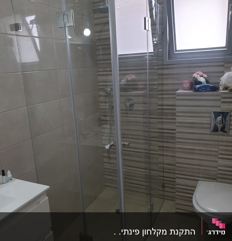 מקלחון זכוכית עם ראש מקלחת וקירות אריחים